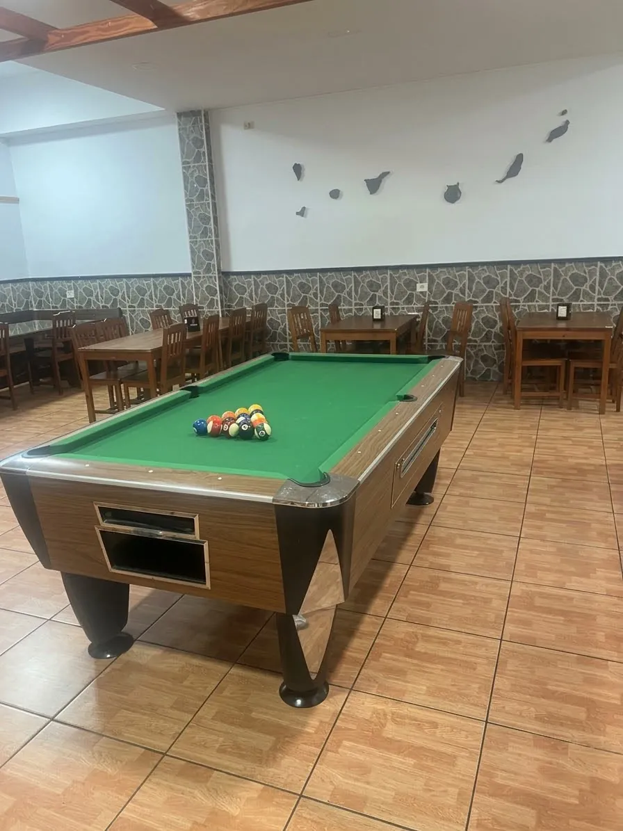 Mesa de billar en el salón de Las Mesas Café Bar, con mesas de madera al fondo